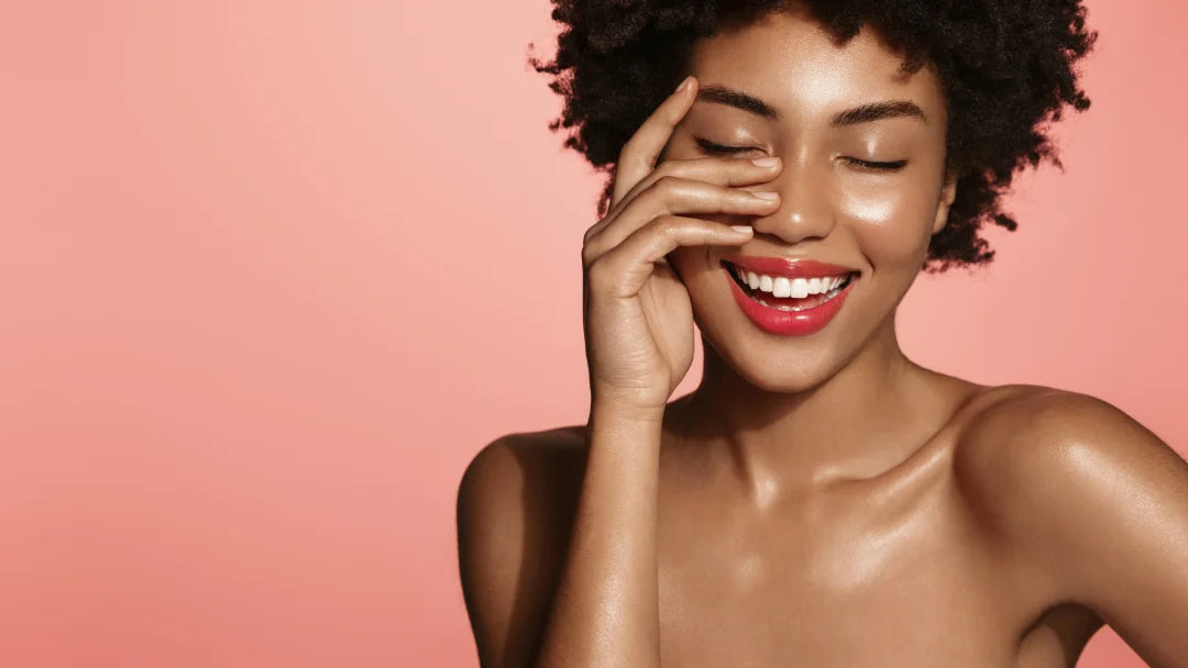 woman smiling with eyes closed on a pink background